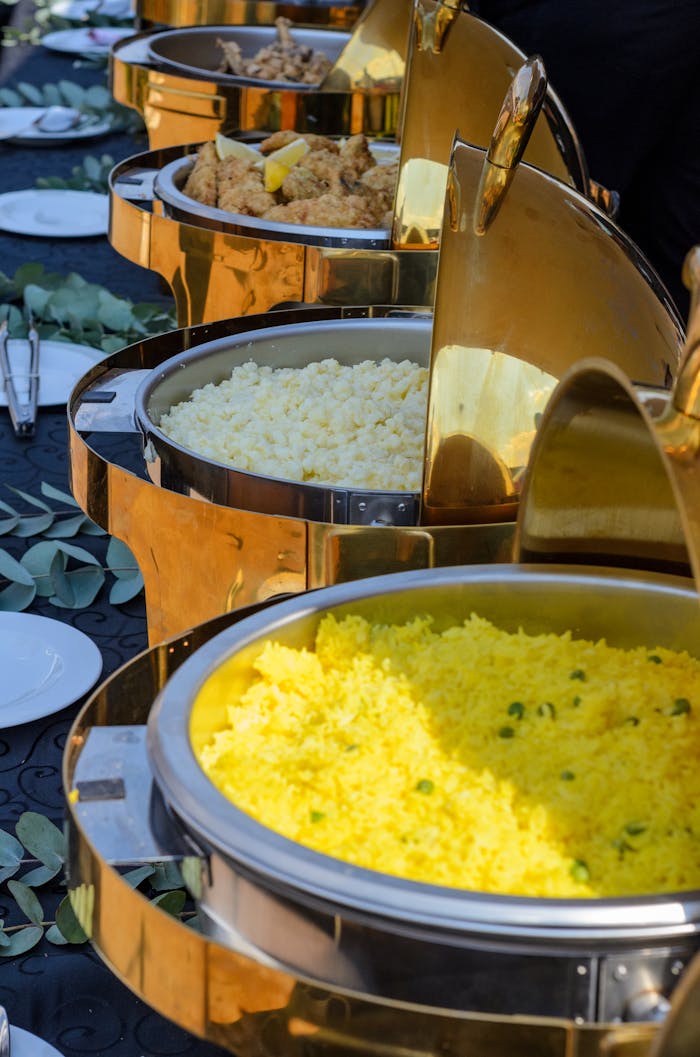 A vibrant buffet spread featuring yellow rice and various options in elegant chafing dishes.
