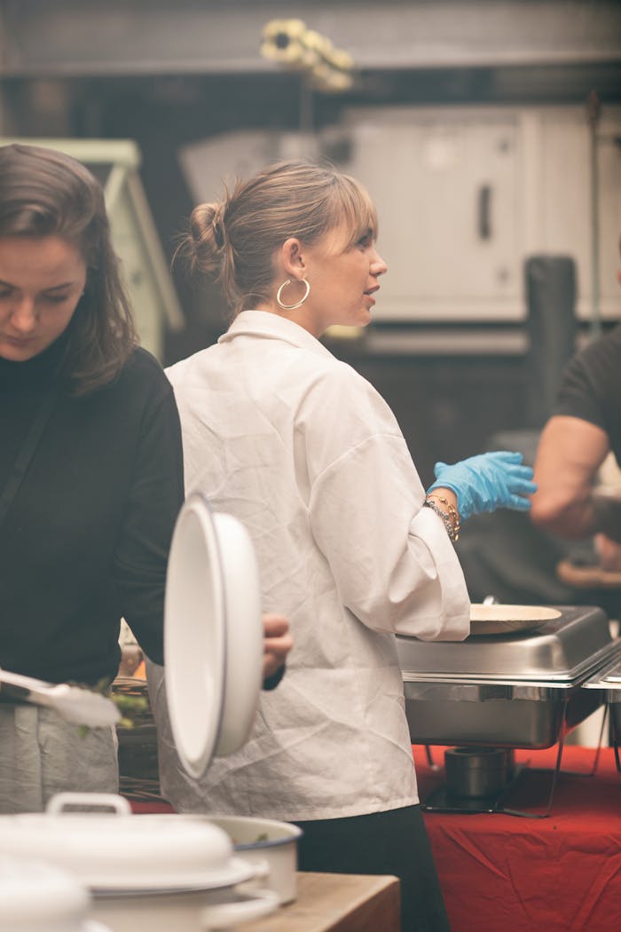 Chefs in a bustling kitchen environment, preparing dishes for an indoor event.