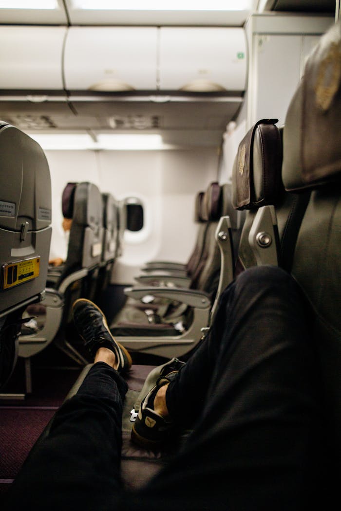 Person relaxing with legs stretched in an empty airplane cabin during flight.
