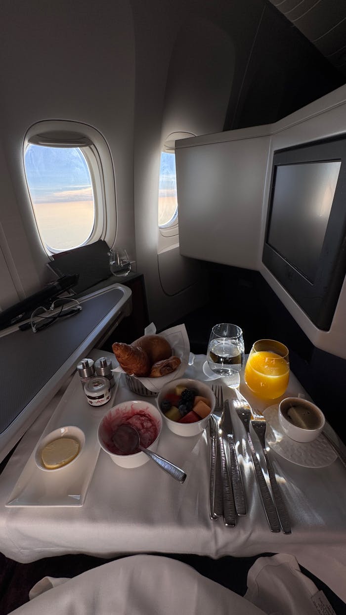 Luxurious first class breakfast setup with croissants and juice on a plane.