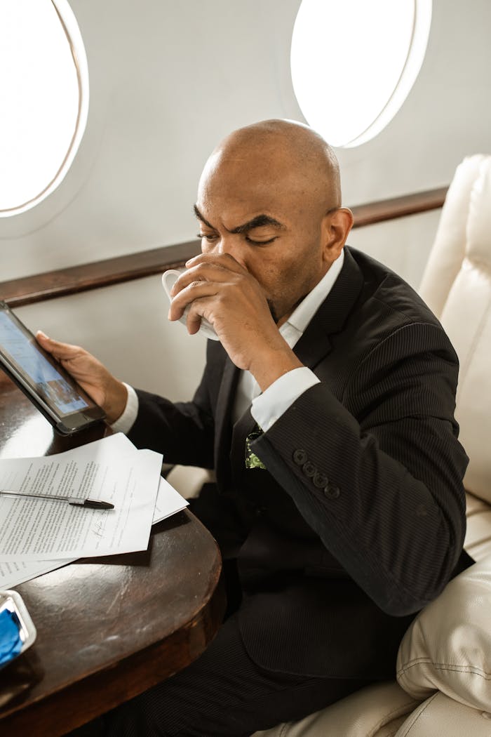 Businessman in suit sipping a drink while working on a flight.