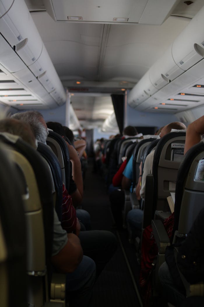 View from the back of an airplane cabin with passengers seated, showcasing travel atmosphere.