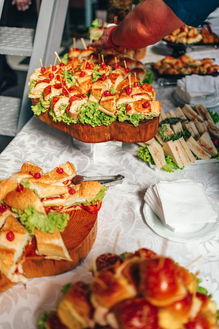 Close-up of a vibrant sandwich buffet with fresh lettuce and garnish on a tablecloth.